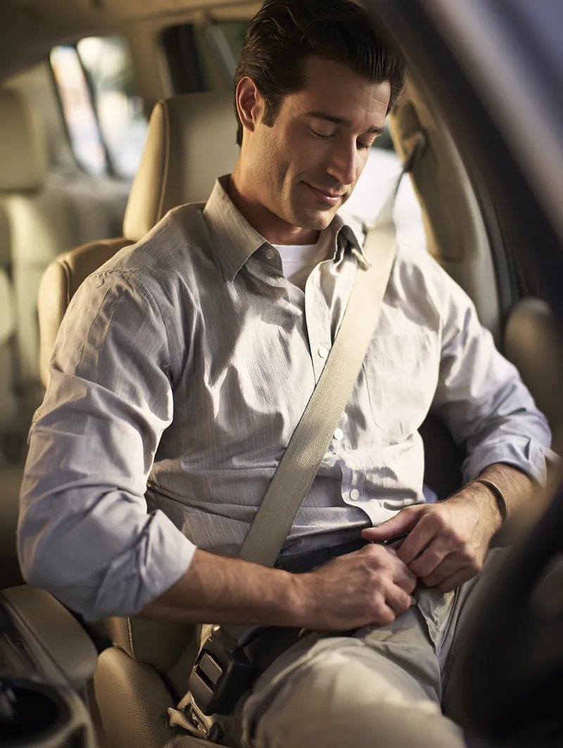 Man buckling his seat belt in a modern SUV in morning light, ready to go once his loan funds arrive