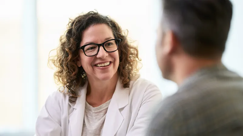 Doctor talking warmly with a patient in a bright consultation room as he plans how to handle a bill without draining his money stash
